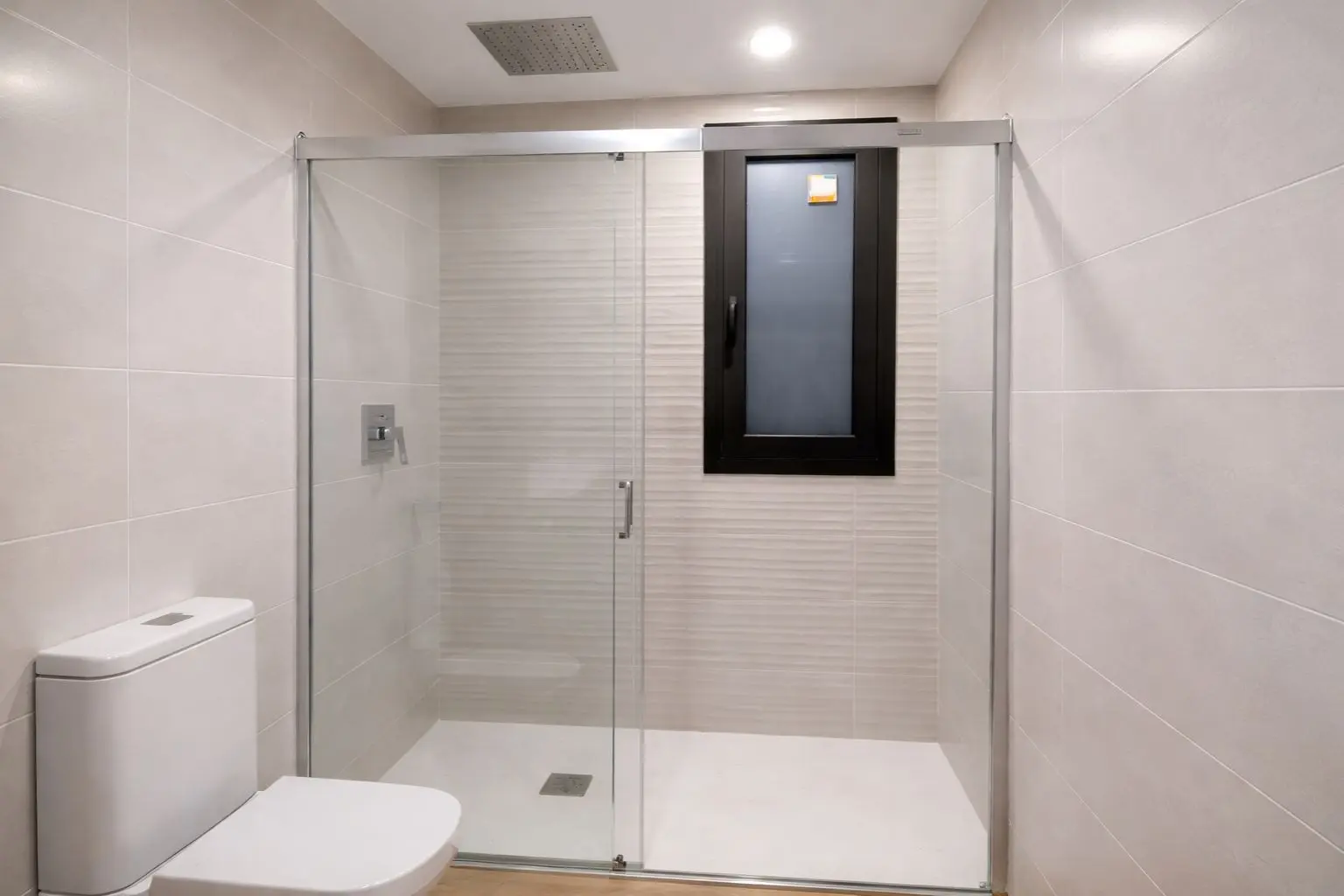 Baño reformado con plato de ducha y mampara tras cambio de bañera en Lloret de Mar