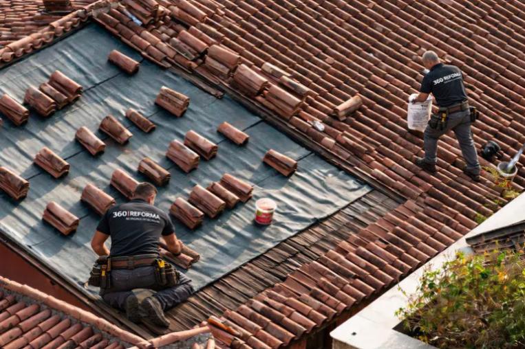 Trabajadores reparando cubierta de tejas durante una rehabilitación de vivienda