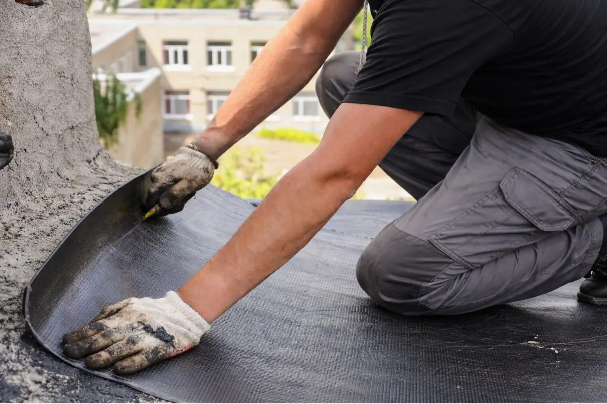 Colocación de tela asfáltica durante impermeabilización de cubierta
